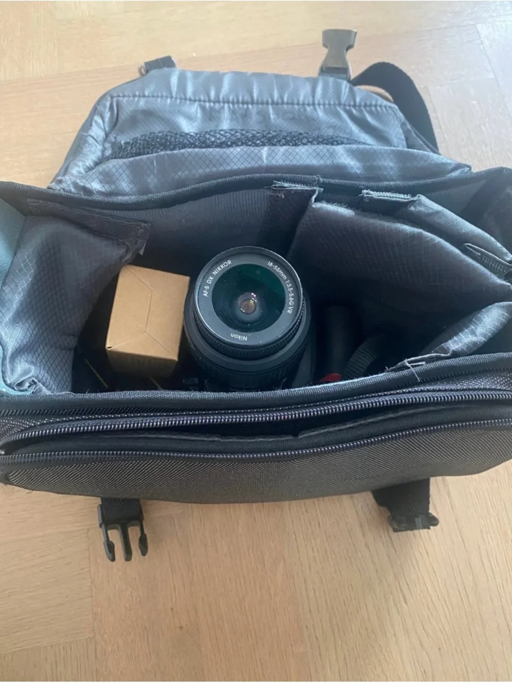 Nikon 3100 black DSLR with zoom lens and attached USB cable